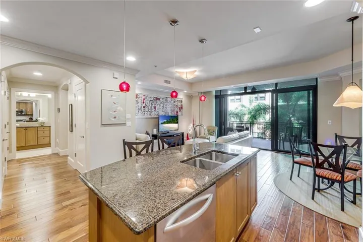 Kitchen island featuring a double-basin stainless steel sink, granite countertop, and light wood cabinetry