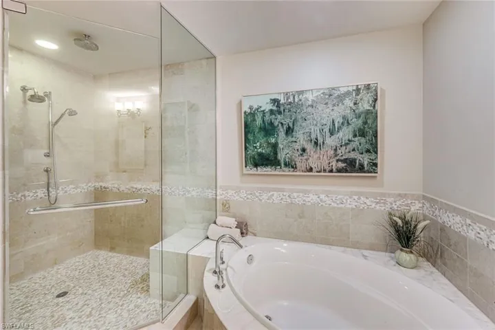 Tiled walk-in shower with glass enclosure, dual shower heads, and built-in bench seating