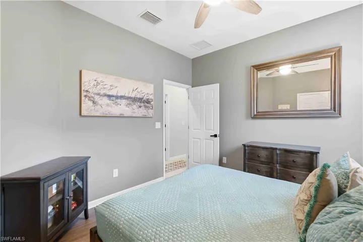 Spacious room featuring wood-finish flooring, a ceiling fan with light fixture, and light gray wall paint