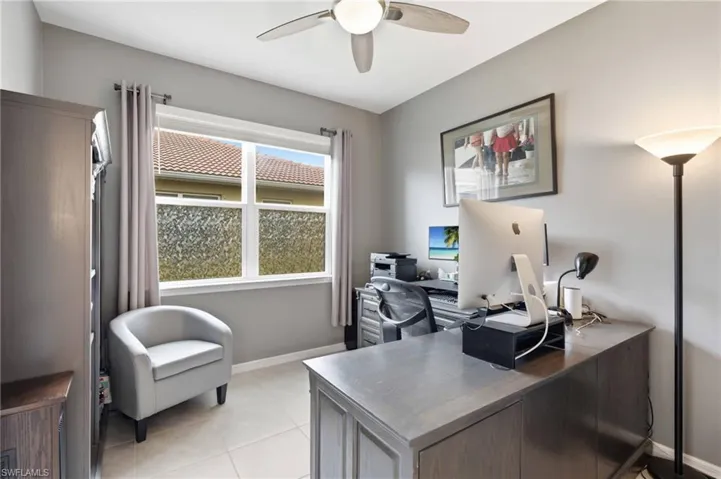 Versatile room featuring a large window with privacy film, tile flooring, and a ceiling fan