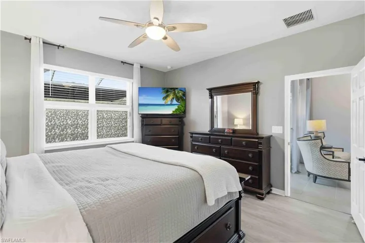 Bedroom featuring light grey walls, a ceiling fan with integrated lighting, and wood-finish flooring