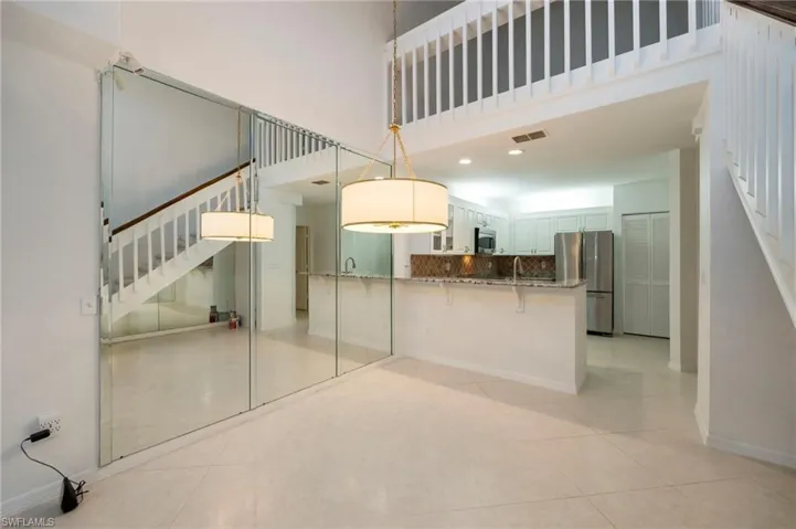 Kitchen with stainless steel appliances, a breakfast bar, hanging light fixtures, a high ceiling, and tasteful backsplash