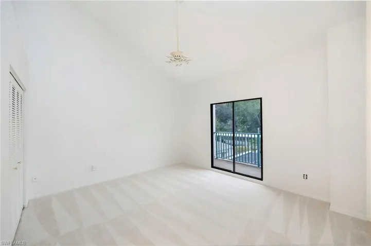 Unfurnished bedroom with light carpet, ceiling fan, lofted ceiling, access to exterior, and a closet