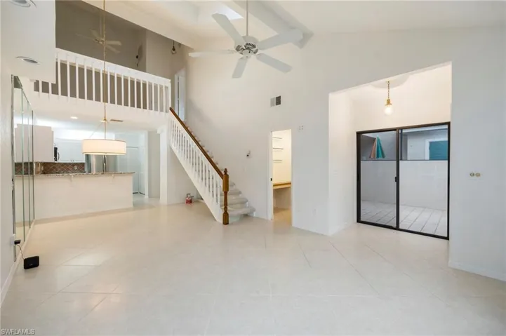 Unfurnished living room with a ceiling fan, light tile patterned floors, and lofted ceiling