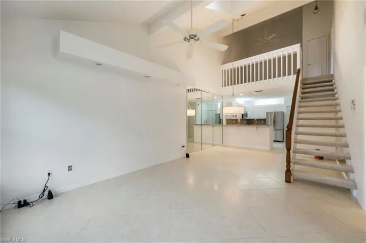 Unfurnished living room featuring a ceiling fan, light tile patterned floors, and lofted ceiling