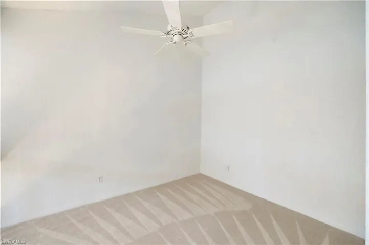 Spare room featuring a ceiling fan and light carpet