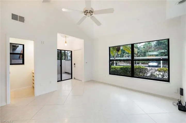 Unfurnished room featuring vaulted ceiling, a ceiling fan, and light tile patterned floors