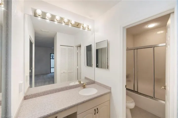 Full bath featuring vanity, combined bath / shower with glass door, light tile patterned flooring, and a closet