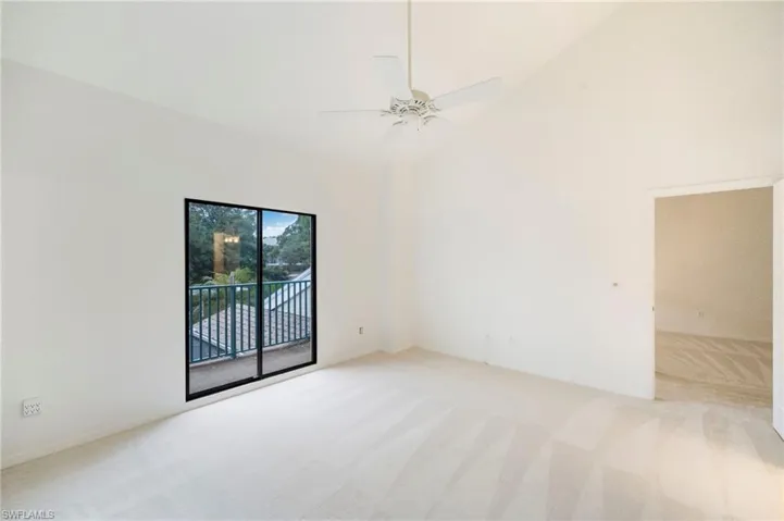Empty room with light carpet, vaulted ceiling, and ceiling fan