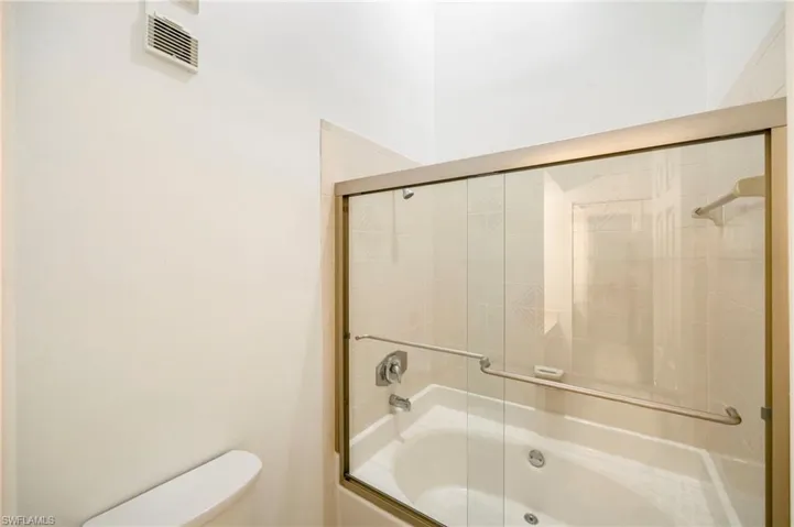 Full bathroom with enclosed tub / shower combo and toilet