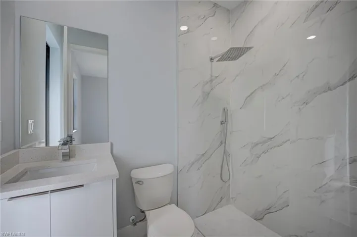 Full bathroom featuring a marble finish shower and vanity