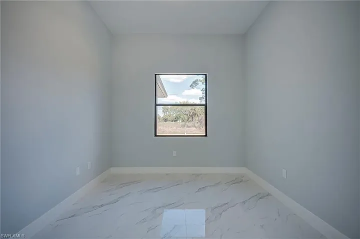 Empty room featuring light marble finish flooring and baseboards