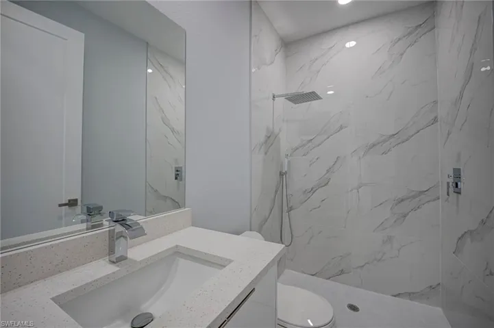 Bathroom featuring vanity and a marble finish shower