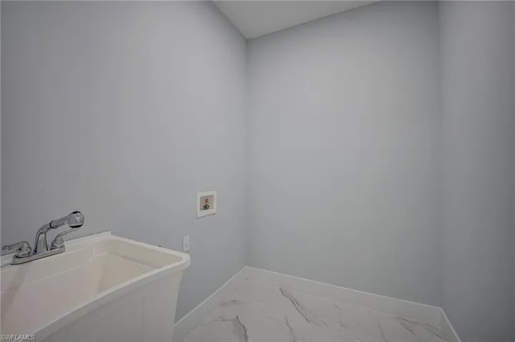 Laundry room featuring washer hookup and light marble finish floors