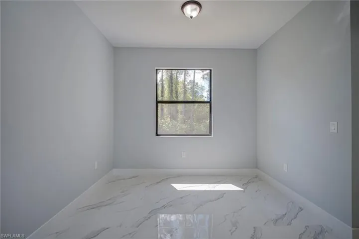 Spare room with light marble finish flooring and baseboards