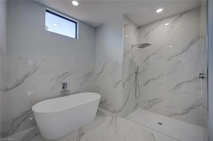 Full bathroom with a marble finish shower, recessed lighting, a freestanding bath, tile walls, and marble tiled flooring