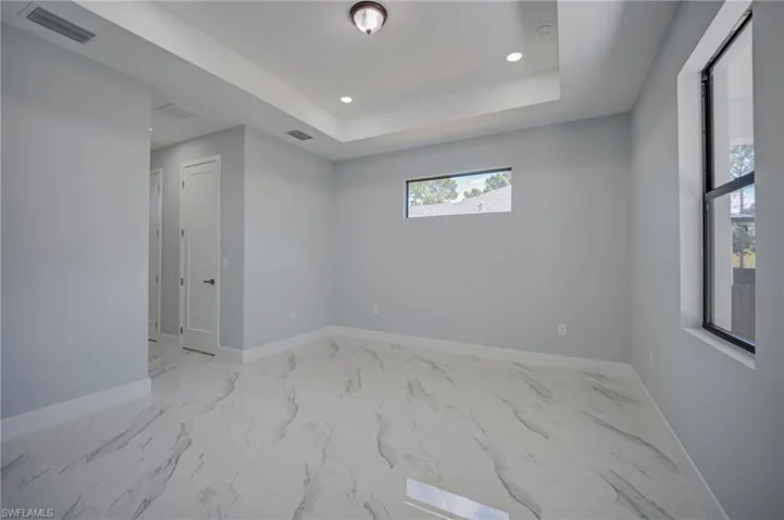Spare room featuring recessed lighting, a tray ceiling, and light marble finish floors