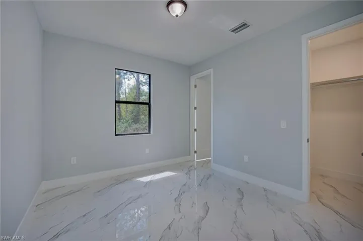 Unfurnished bedroom with a spacious closet and light marble finish floors