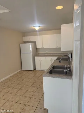 Kitchen with fridge, white cabinets, and light tile patterned floors