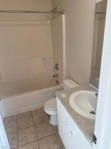 Full bath with vanity, light tile patterned floors, and bathing tub / shower combination