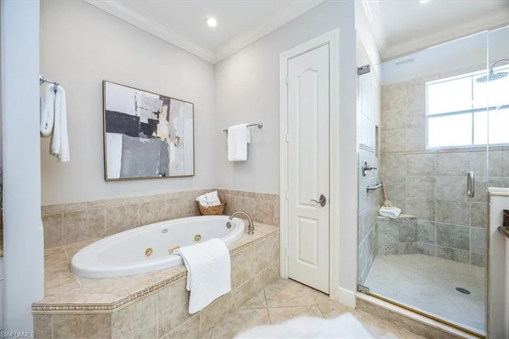 Bathroom featuring crown molding, plus walk in shower, and tile patterned floors
