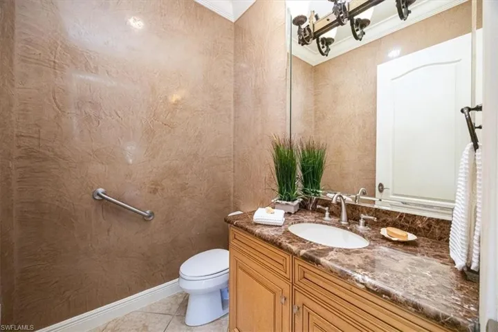 Bathroom featuring vanity, toilet, crown molding, and tile patterned floors