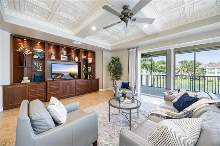 Tiled living room with ceiling fan and coffered ceiling