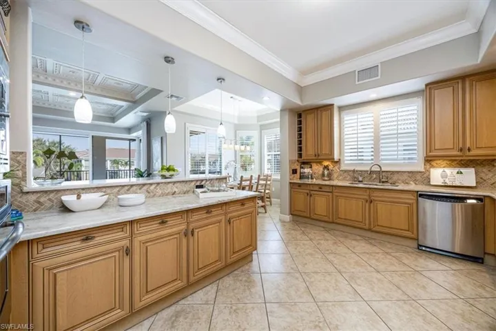 Kitchen with decorative backsplash, a healthy amount of sunlight, stainless steel dishwasher, and hanging light fixtures