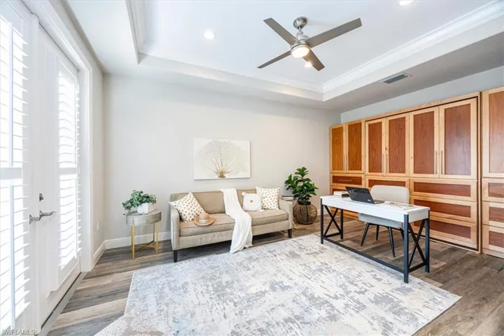Den/Office/ 4th bedroom area with hardwood / wood-style floors, ceiling fan, crown molding, and a raised ceiling