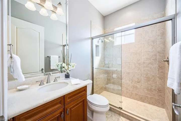Bathroom featuring vanity, tile patterned floors, toilet, and an enclosed shower