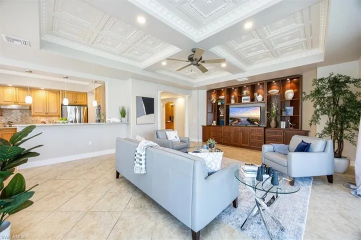 Tiled living room featuring ceiling fan, coffered ceiling, and beam ceiling
