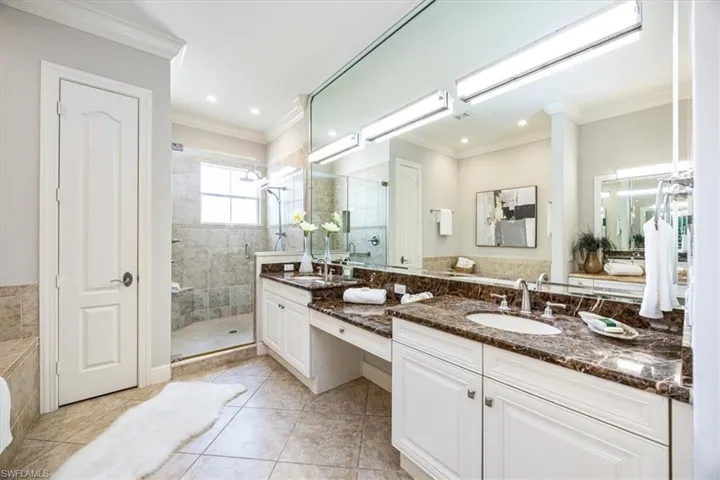 Bathroom with vanity, ornamental molding, a tile shower, and tile patterned flooring