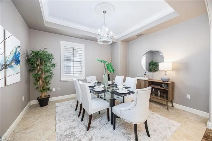 Dining area featuring crown molding, a tray ceiling, and an inviting chandelier