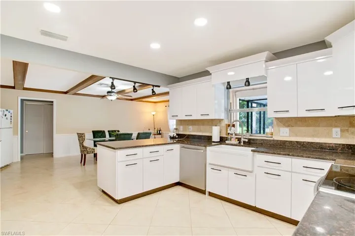 Kitchen featuring kitchen peninsula, tasteful backsplash, ceiling fan, stainless steel dishwasher, and beamed ceiling
