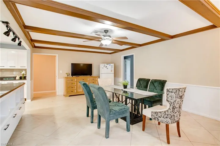 Tiled dining space featuring beamed ceiling, ornamental molding, and ceiling fan
