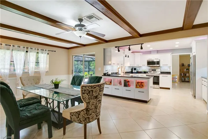 Tiled dining room featuring sink, ceiling fan, ornamental molding, and beam ceiling