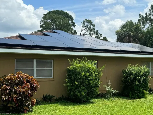 View of side of home featuring a lawn and solar panels