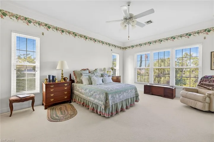 Carpeted bedroom featuring a ceiling fan and crown molding