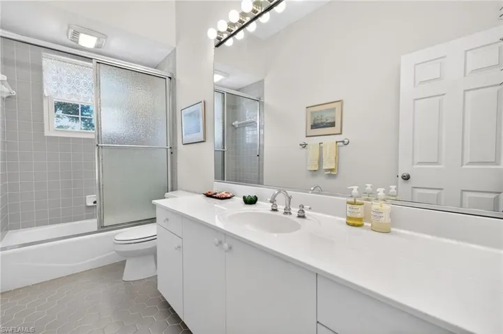 Full bath featuring vanity, light tile patterned floors, and shower / bath combination with glass door