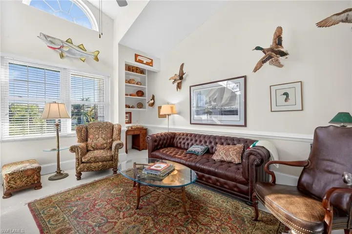 Living area with built in shelves, healthy amount of natural light, a ceiling fan, and lofted ceiling