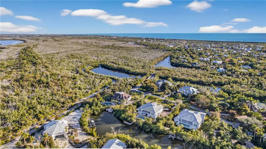 Aerial perspective of suburban area featuring a nearby body of water and a heavily wooded area