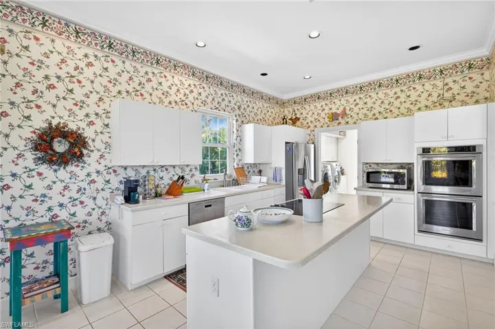 Kitchen featuring separate washer and dryer, stainless steel appliances, crown molding, light countertops, and white cabinetry