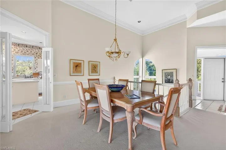 Dining area with light colored carpet, a chandelier, ornamental molding, and healthy amount of natural light
