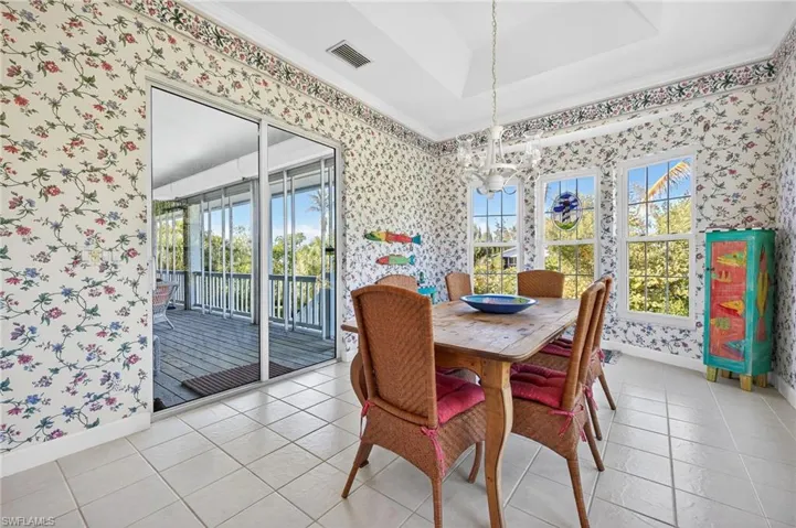 Dining area with crown molding, wallpapered walls, and light tile patterned floors