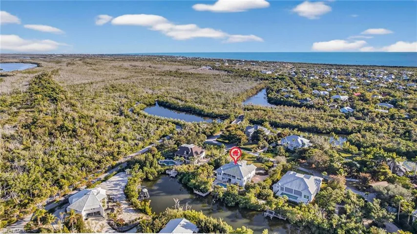 Aerial view of residential area featuring a large body of water and a forest