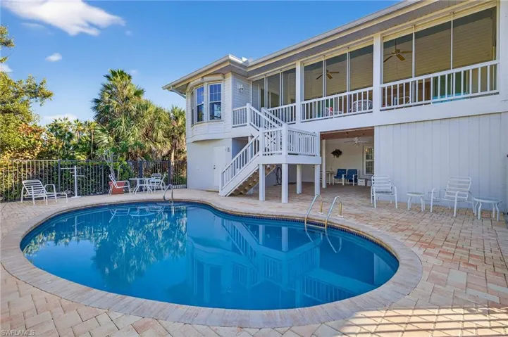 View of swimming pool with patio surround, a sunroom, and a deck