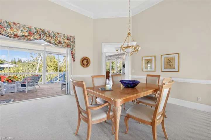 Dining area featuring carpet flooring, ornamental molding, a high ceiling, and suspended lighting