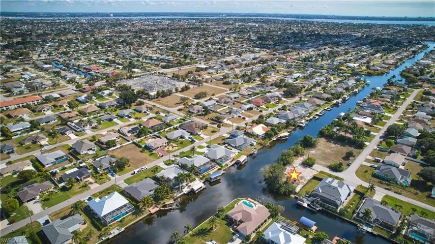 Aerial view of property and surrounding area featuring nearby suburban area and a large body of water