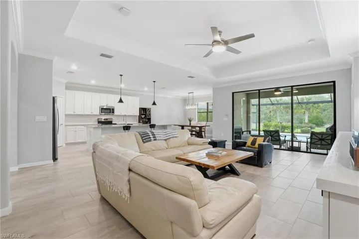 Open-concept interior featuring light gray wall tones, tile flooring, a tray ceiling, and a ceiling fan