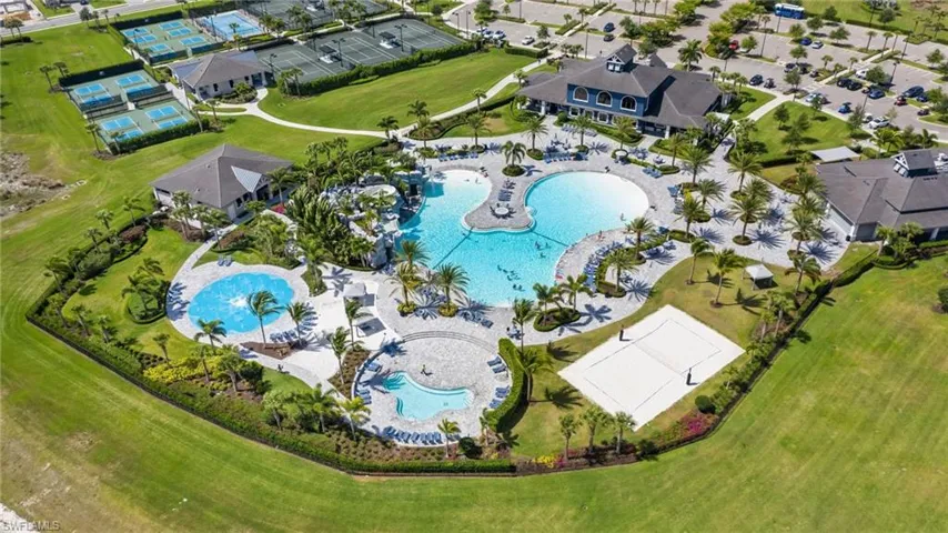 Expansive amenity center featuring multiple swimming pools, a sand volleyball court, tennis courts, and a club house building
